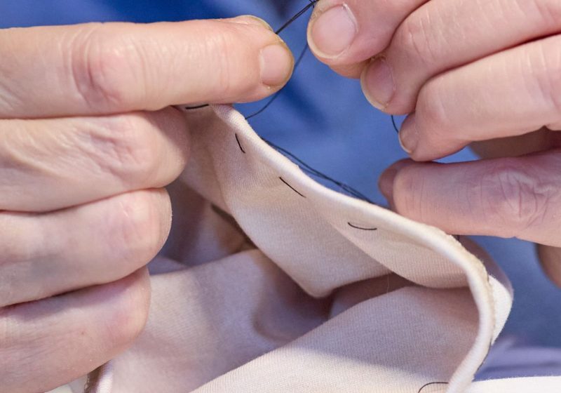 Hands sewing fabric by hand